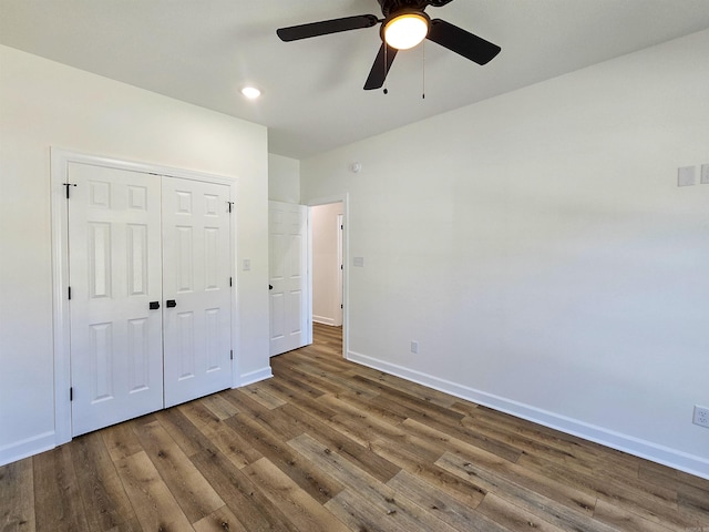 unfurnished bedroom with dark hardwood / wood-style flooring, ceiling fan, and a closet