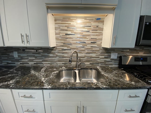 kitchen featuring white cabinets, sink, dark stone countertops, tasteful backsplash, and range with gas cooktop