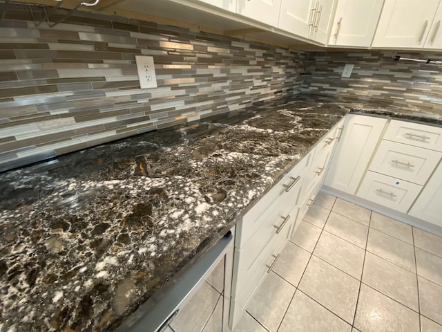 kitchen with white cabinets, light tile patterned floors, backsplash, and dark stone counters