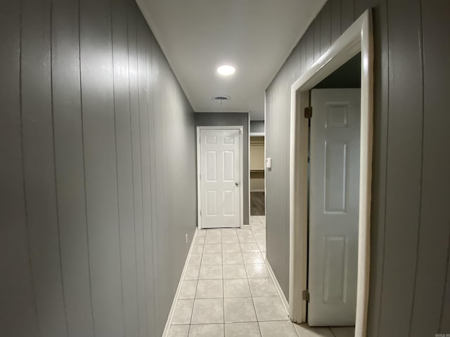 hallway with wood walls and light tile patterned floors