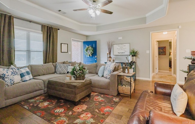 living room featuring hardwood / wood-style flooring, ceiling fan, crown molding, and a tray ceiling