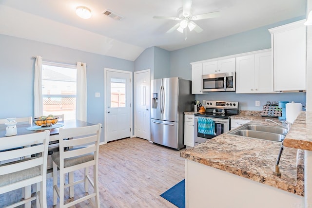 kitchen featuring light stone countertops, stainless steel appliances, sink, white cabinetry, and lofted ceiling