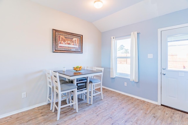 dining room with light hardwood / wood-style flooring and lofted ceiling