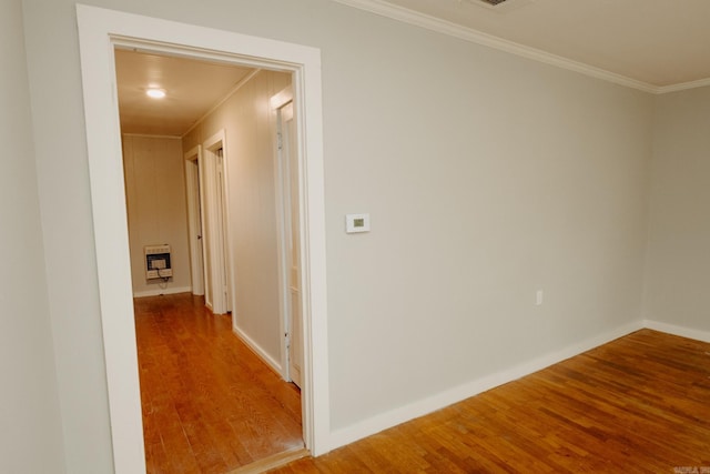 hall featuring heating unit, hardwood / wood-style floors, and ornamental molding