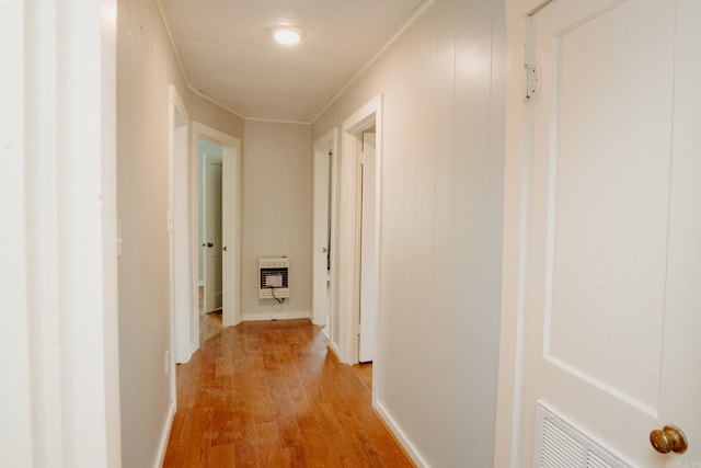 hall featuring heating unit, crown molding, light hardwood / wood-style floors, and wood walls