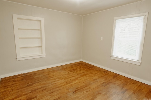 unfurnished room featuring hardwood / wood-style flooring and built in shelves