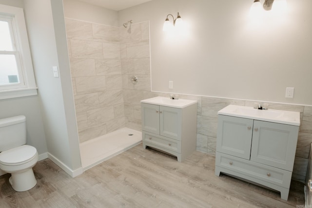 bathroom featuring tiled shower, wood-type flooring, vanity, and toilet