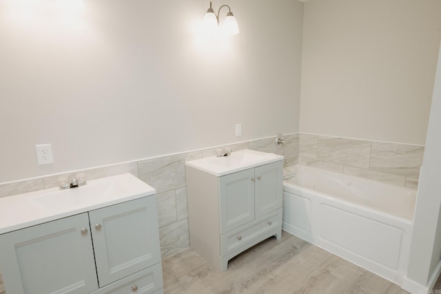 bathroom with a tub to relax in, hardwood / wood-style floors, vanity, and tile walls