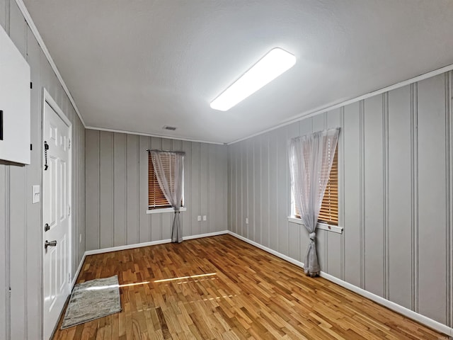 unfurnished room with hardwood / wood-style flooring and crown molding