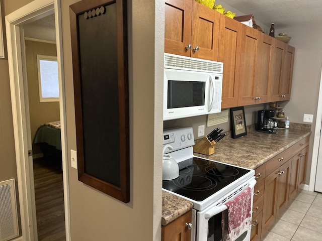 kitchen with crown molding, white appliances, and light tile patterned floors