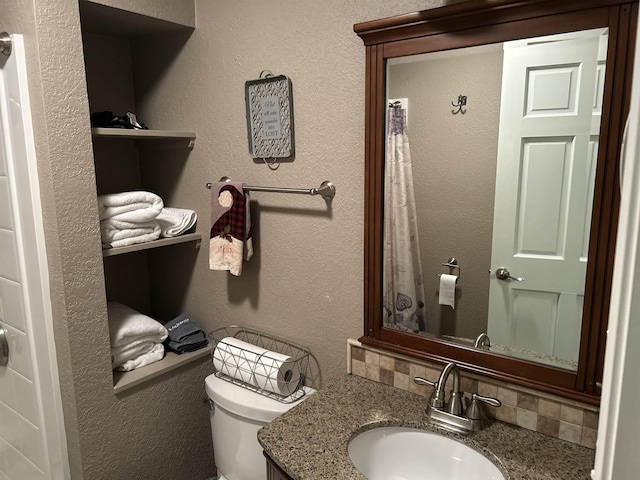 bathroom with vanity, backsplash, and toilet