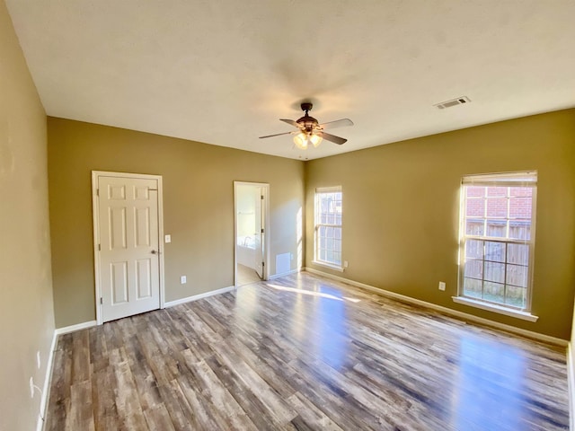 unfurnished bedroom with ceiling fan, light hardwood / wood-style floors, multiple windows, and ensuite bath