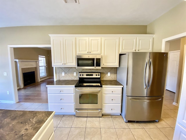 kitchen featuring white cabinets, appliances with stainless steel finishes, decorative backsplash, and light tile patterned floors