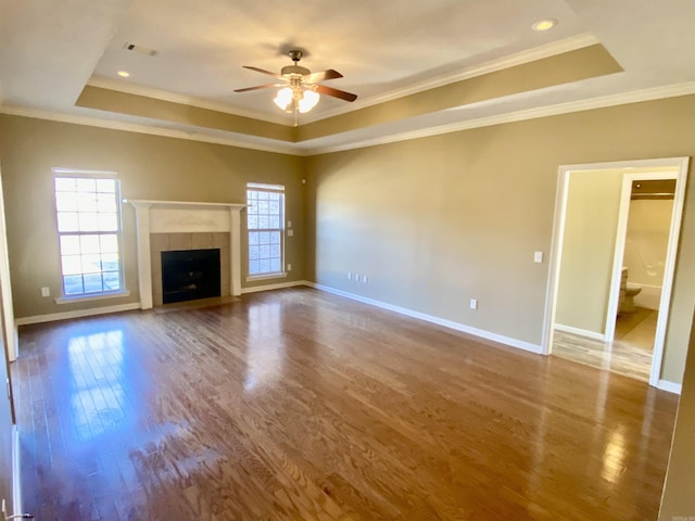 unfurnished living room featuring a tray ceiling, ornamental molding, and a tiled fireplace