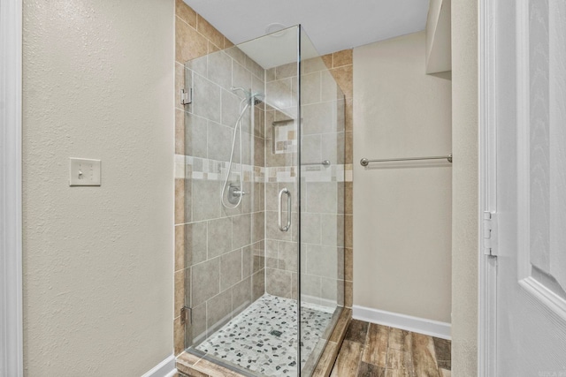 bathroom with a shower with shower door and wood-type flooring