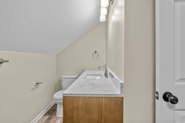 bathroom with hardwood / wood-style floors, vanity, toilet, and vaulted ceiling