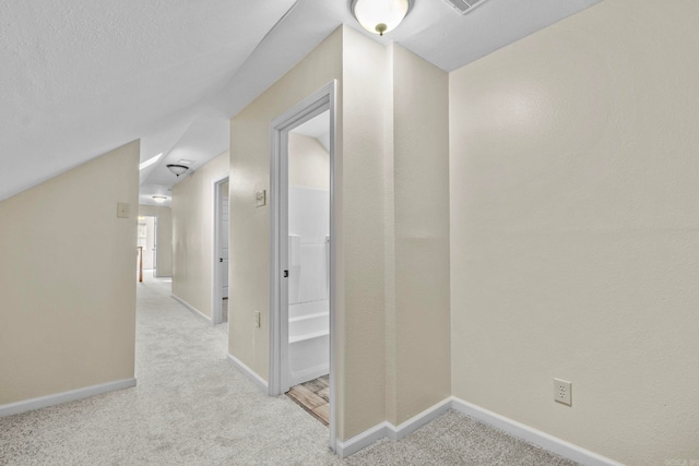 hallway featuring light carpet and vaulted ceiling