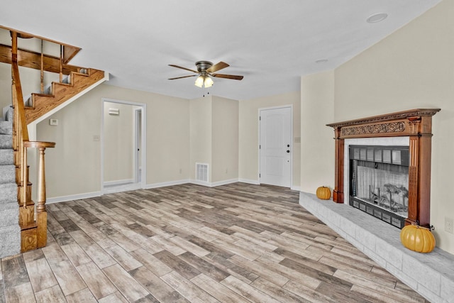 unfurnished living room with light hardwood / wood-style floors, a brick fireplace, and ceiling fan