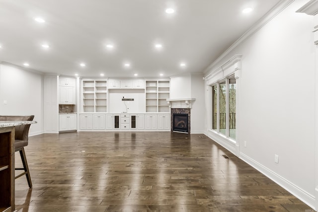 unfurnished living room with dark hardwood / wood-style floors, crown molding, and a high end fireplace