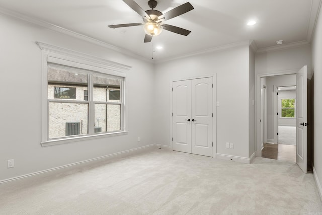 unfurnished bedroom with a closet, light colored carpet, ceiling fan, and ornamental molding