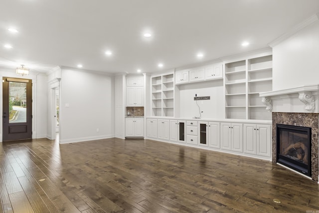 unfurnished living room with dark hardwood / wood-style floors, a premium fireplace, and crown molding