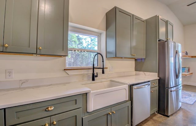 kitchen with vaulted ceiling, stainless steel appliances, light stone counters, and sink