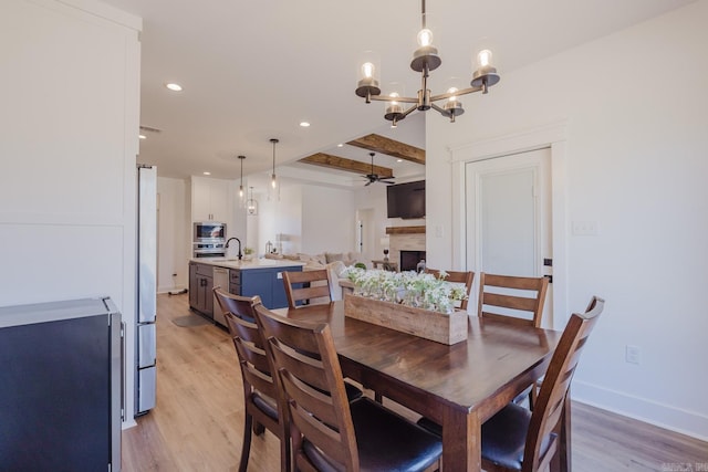 dining space featuring beam ceiling, ceiling fan with notable chandelier, and light hardwood / wood-style floors