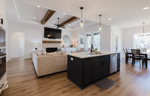 kitchen with hanging light fixtures, an island with sink, stainless steel appliances, and sink