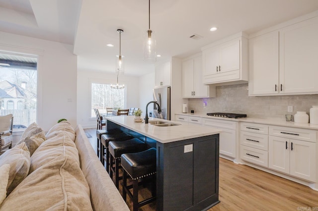 kitchen with stainless steel refrigerator, sink, white cabinets, and pendant lighting