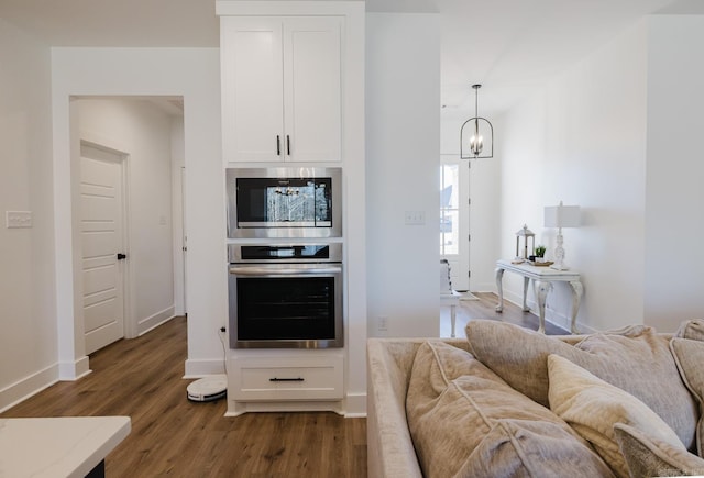 kitchen featuring appliances with stainless steel finishes, an inviting chandelier, white cabinetry, and pendant lighting