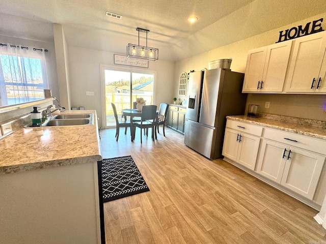 kitchen featuring stainless steel fridge, white cabinetry, pendant lighting, and sink