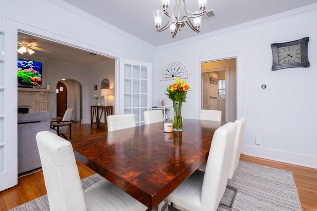 dining room featuring wood-type flooring, ceiling fan with notable chandelier, and crown molding