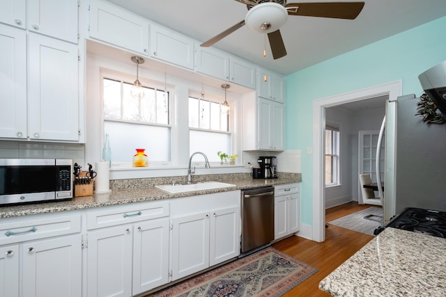 kitchen featuring white cabinets, appliances with stainless steel finishes, light hardwood / wood-style floors, sink, and backsplash