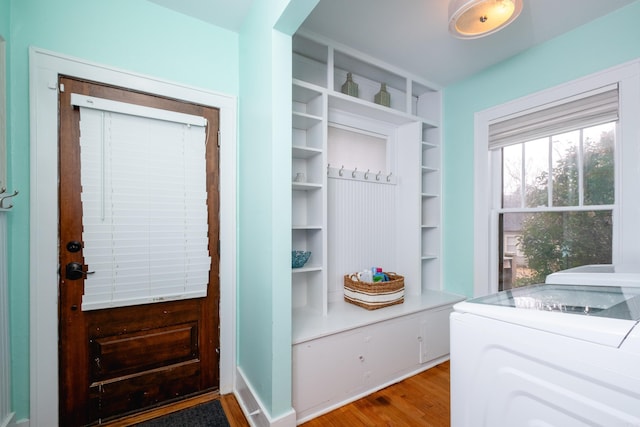 mudroom with built in features, washing machine and clothes dryer, and hardwood / wood-style floors