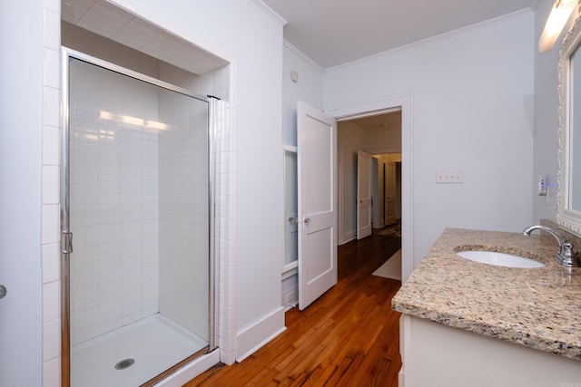 bathroom with hardwood / wood-style flooring, a shower with shower door, ornamental molding, and vanity