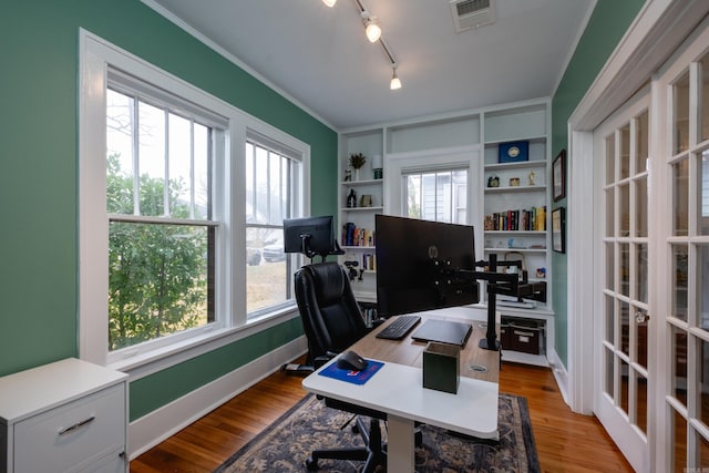 office area featuring light wood-type flooring, track lighting, crown molding, and built in shelves