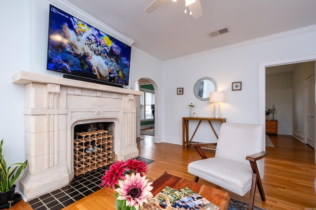 living room featuring ceiling fan, wood-type flooring, and ornamental molding