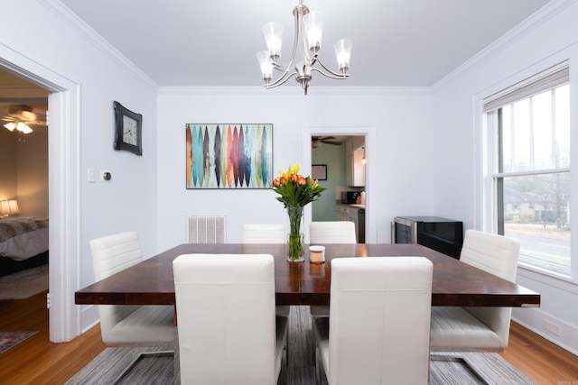 dining area with dark hardwood / wood-style floors, a wealth of natural light, crown molding, and a notable chandelier