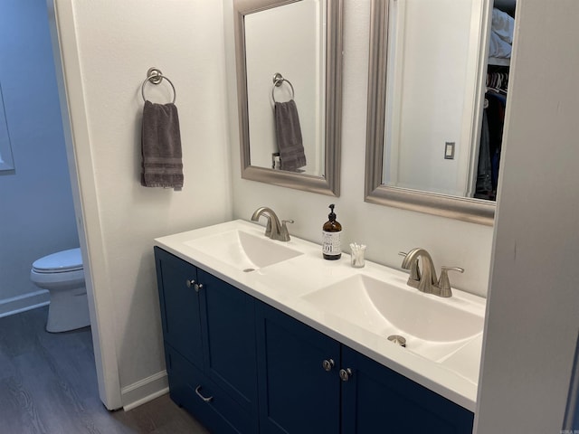 bathroom with wood-type flooring, toilet, and vanity