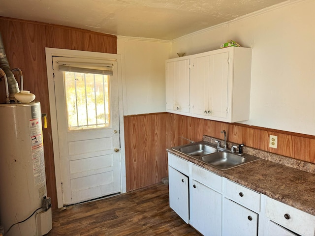 kitchen featuring white cabinetry, sink, gas water heater, dark hardwood / wood-style floors, and wood walls