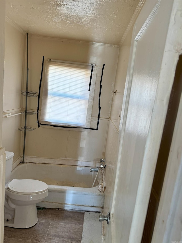 bathroom featuring a bathtub, toilet, and a textured ceiling