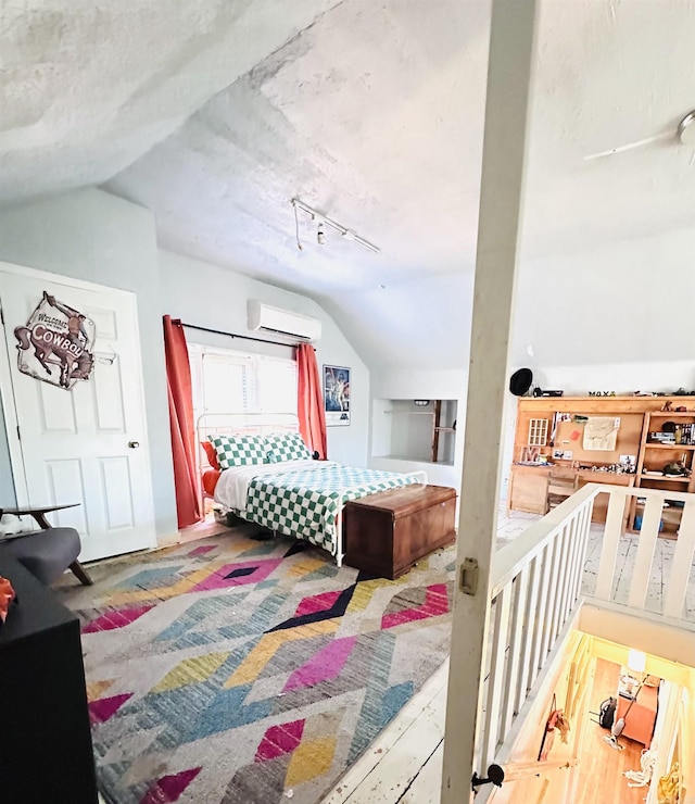 bedroom featuring track lighting, lofted ceiling, and a wall mounted air conditioner