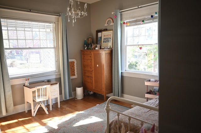 bedroom featuring multiple windows, light hardwood / wood-style flooring, and an inviting chandelier