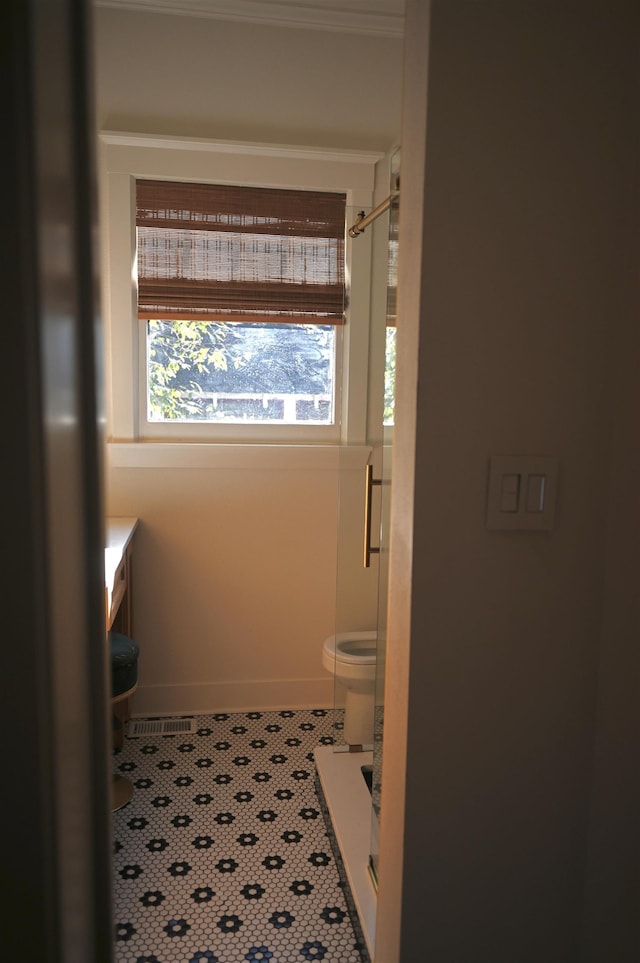 bathroom featuring toilet, a shower, and tile patterned floors