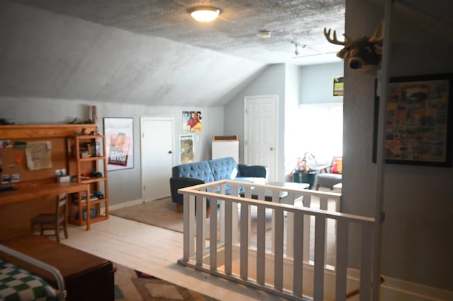 bedroom with a nursery area, lofted ceiling, and wood-type flooring