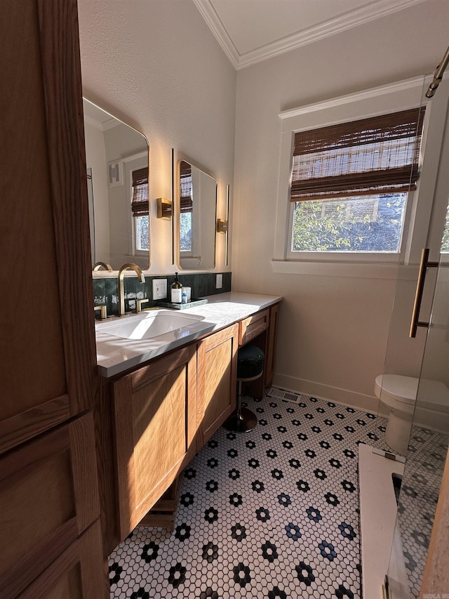 bathroom with toilet, vanity, crown molding, and tile patterned flooring