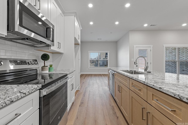 kitchen featuring white cabinetry, sink, stainless steel appliances, and light stone counters