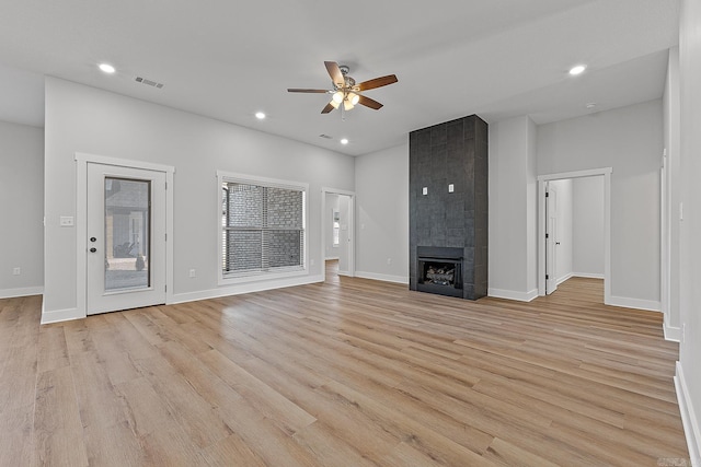 unfurnished living room featuring light wood-type flooring, ceiling fan, and a tiled fireplace