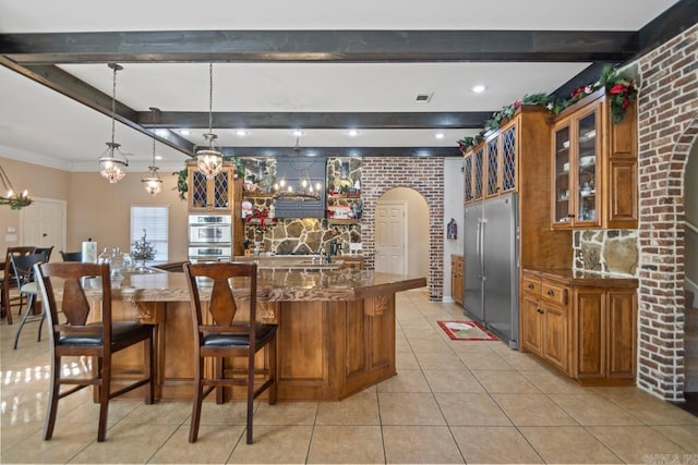 kitchen with stainless steel appliances, dark stone countertops, pendant lighting, a breakfast bar, and light tile patterned floors