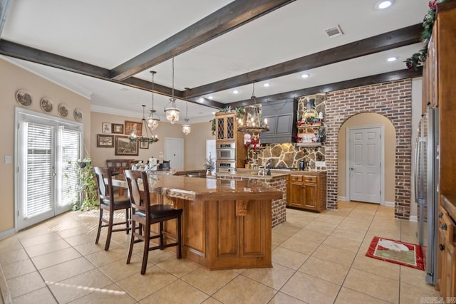 kitchen featuring a breakfast bar, stainless steel double oven, a spacious island, light tile patterned floors, and decorative light fixtures